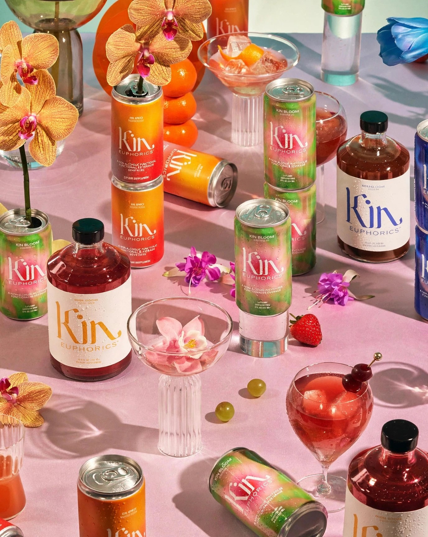 Kin bottles and cans among cocktail glasses and blossoms.