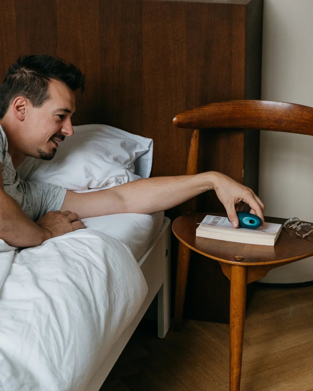 Man in bed reaching for a moonbird on a nightstand.
