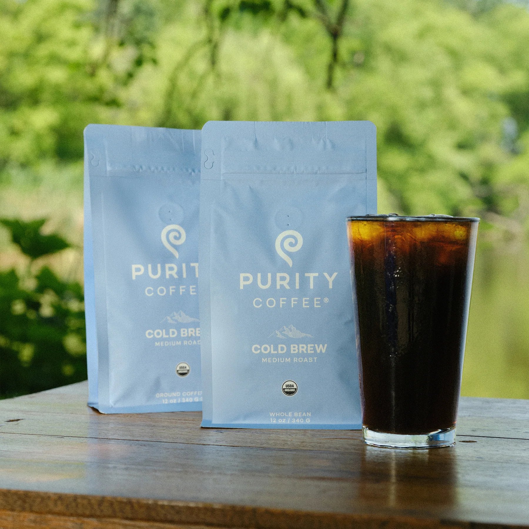 Outdoor table holds Cold Brew bags and brewed coffee glass.